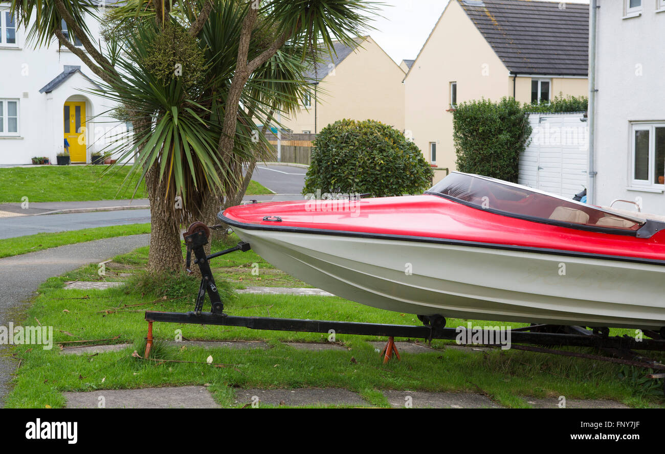 A red speed boat set at rest in the front garden of a UK home on an estate in Wlaes. Stock Photo