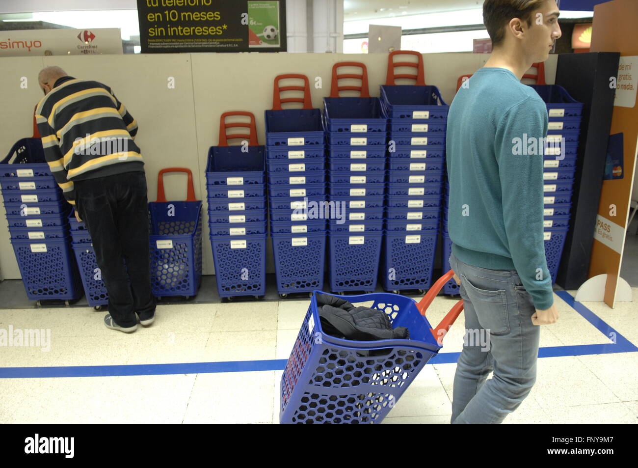 Carrefour Supermarket male customer holding shopping basket past stacks of  baskets in background Stock Photo - Alamy