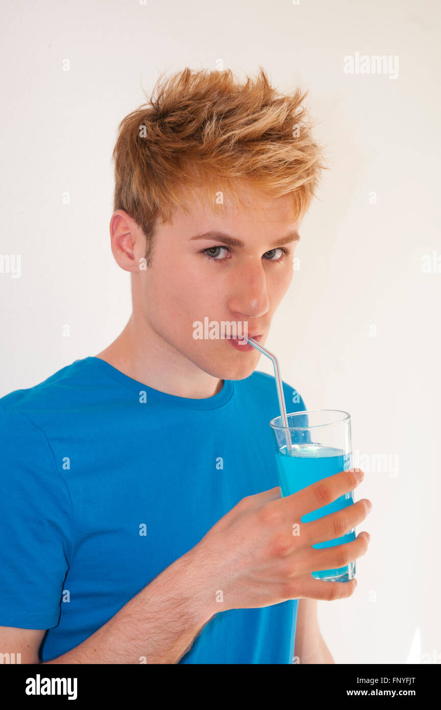 Young man drinking a blue isotonic drink, matching with his T-shirt. Close view. Stock Photo