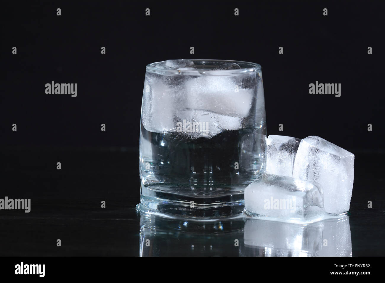 Glass of water with ice cubes on dark background Stock Photo - Alamy