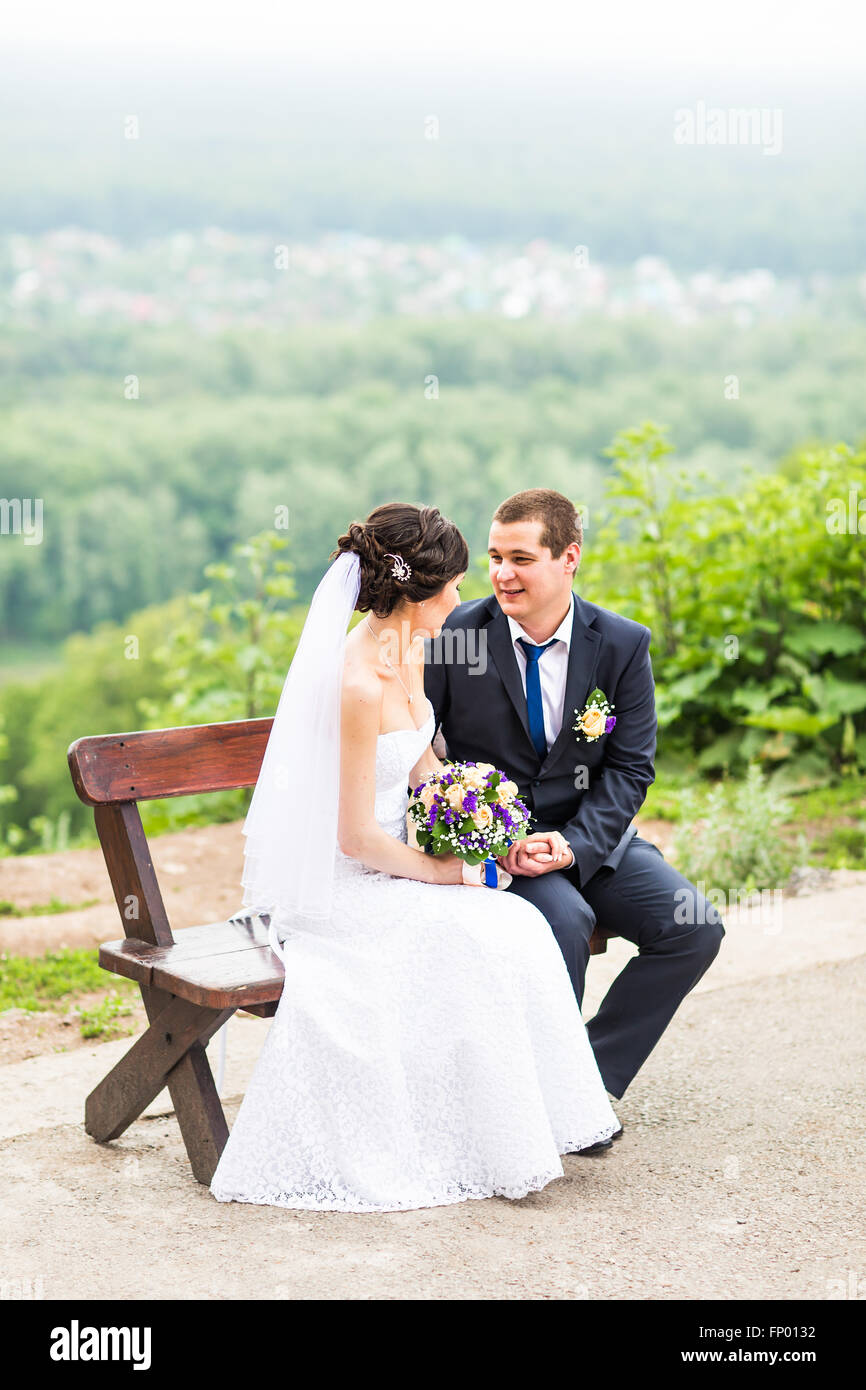 attractive bride and groom sitting on a bench Stock Photo - Alamy