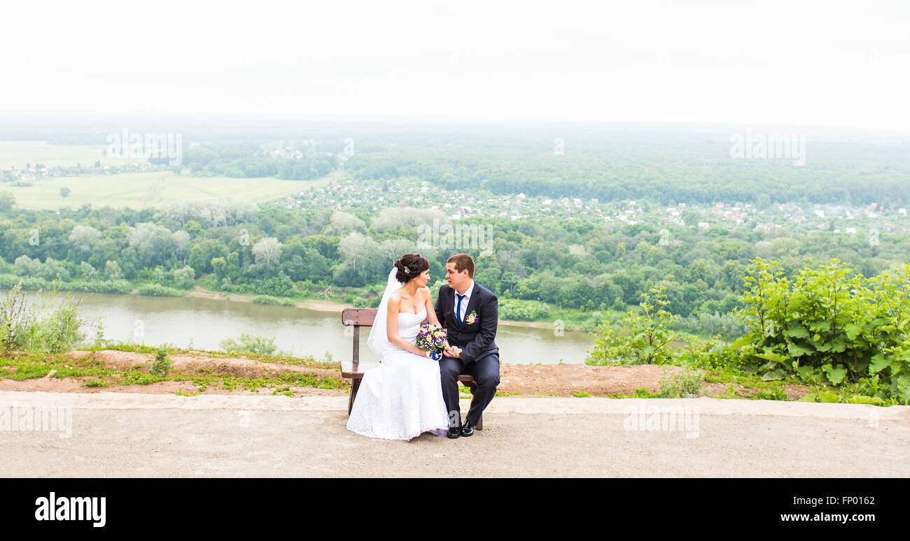 attractive bride and groom sitting on a bench Stock Photo - Alamy