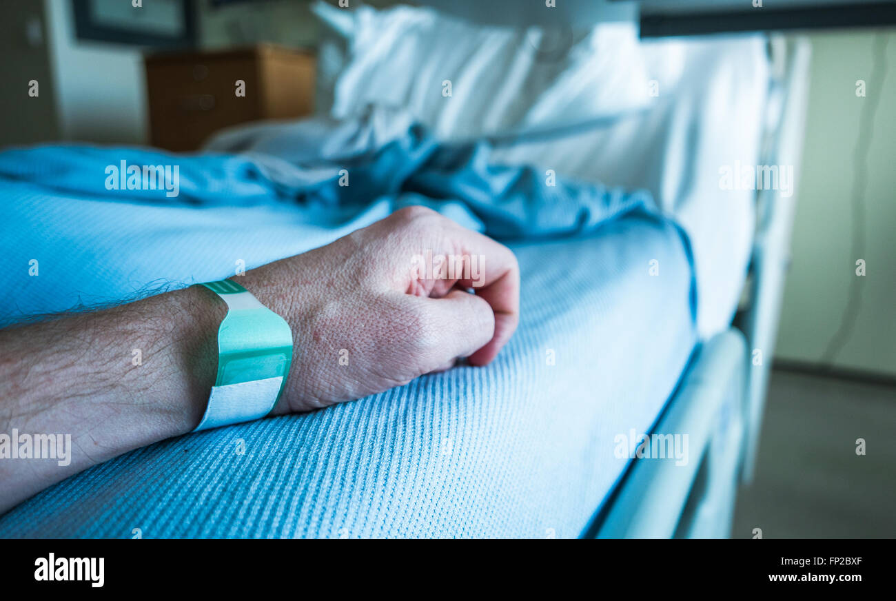 Detail Of A Man's Arm On A Hospital Bed With Wrist Tag Stock Photo