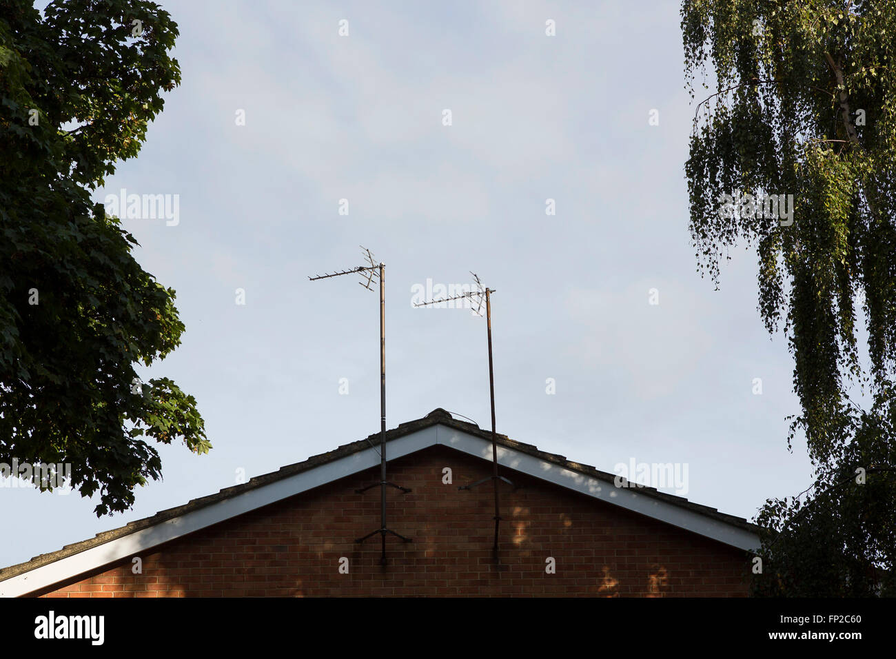 A house roof with two television aerials attached to the side wall. Uk housing in Gloucester. Stock Photo
