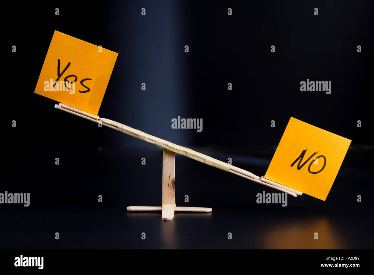 concept of duality using sticky notes with antonyms on a hand made sea saw on a dark background