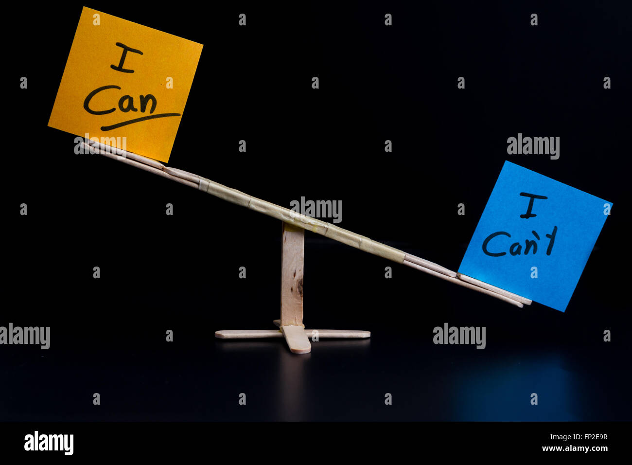 concept of duality using sticky notes with antonyms on a hand made sea saw on a dark background