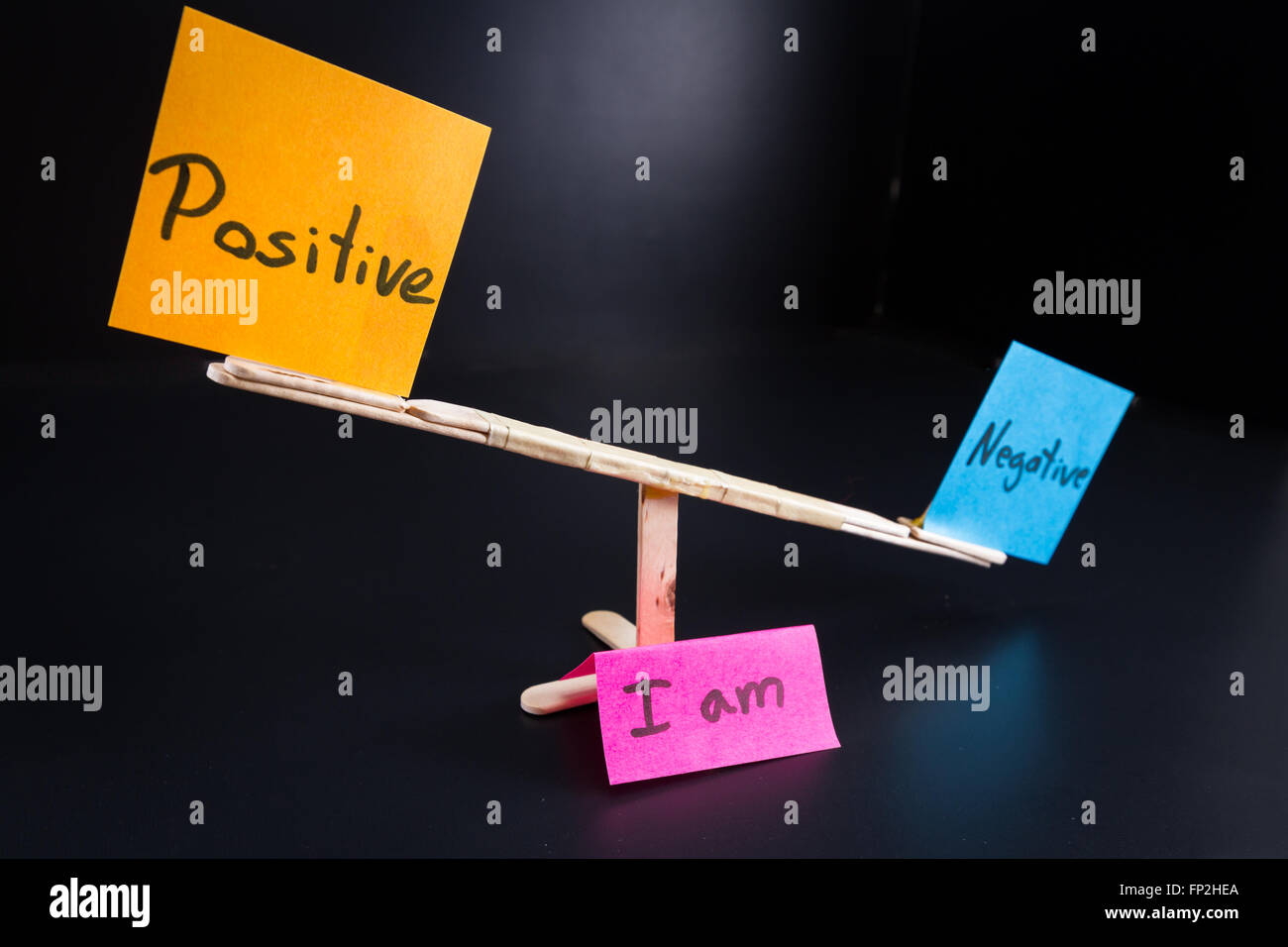 concept of duality using sticky notes with antonyms on a hand made sea saw on a dark background
