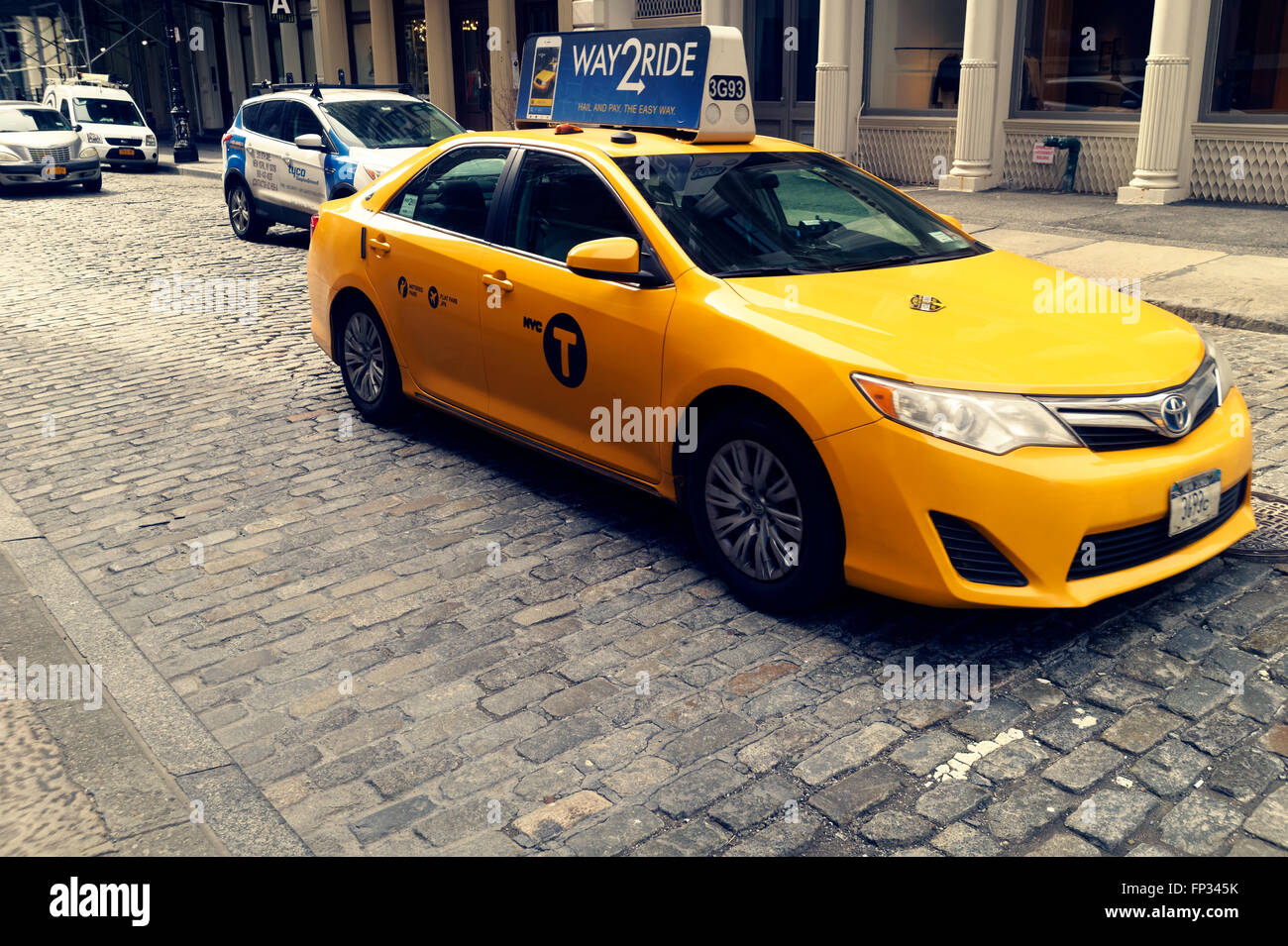 Taxi cab on cobblestone street in the Soho are in New York City. Stock Photo
