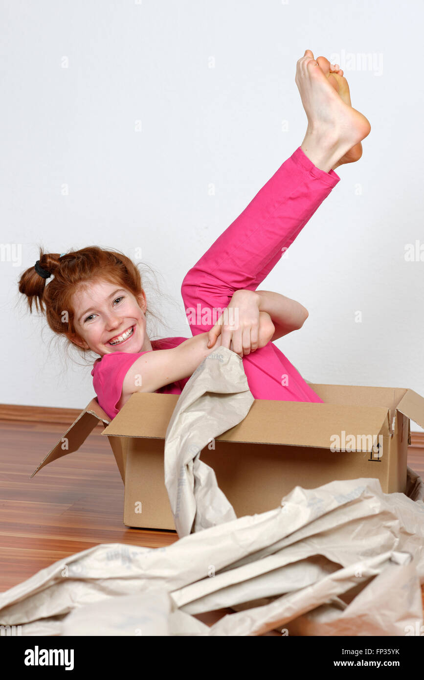 Child sitting in a cardboard box with packaging, Bavaria, Germany Stock Photo