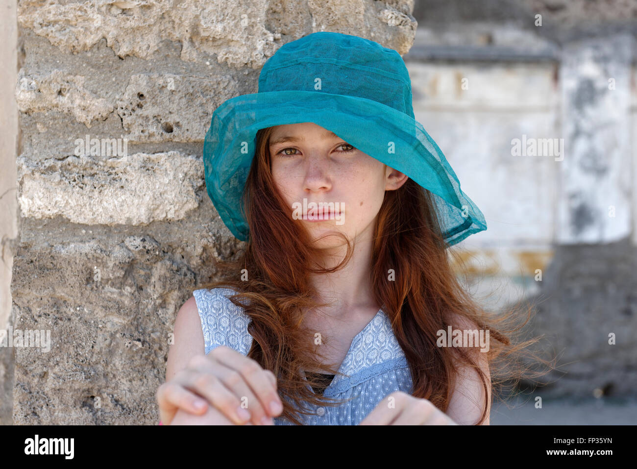 Red-haired girl with a turquoise sun hat looking seriously, portrait, Italy Stock Photo