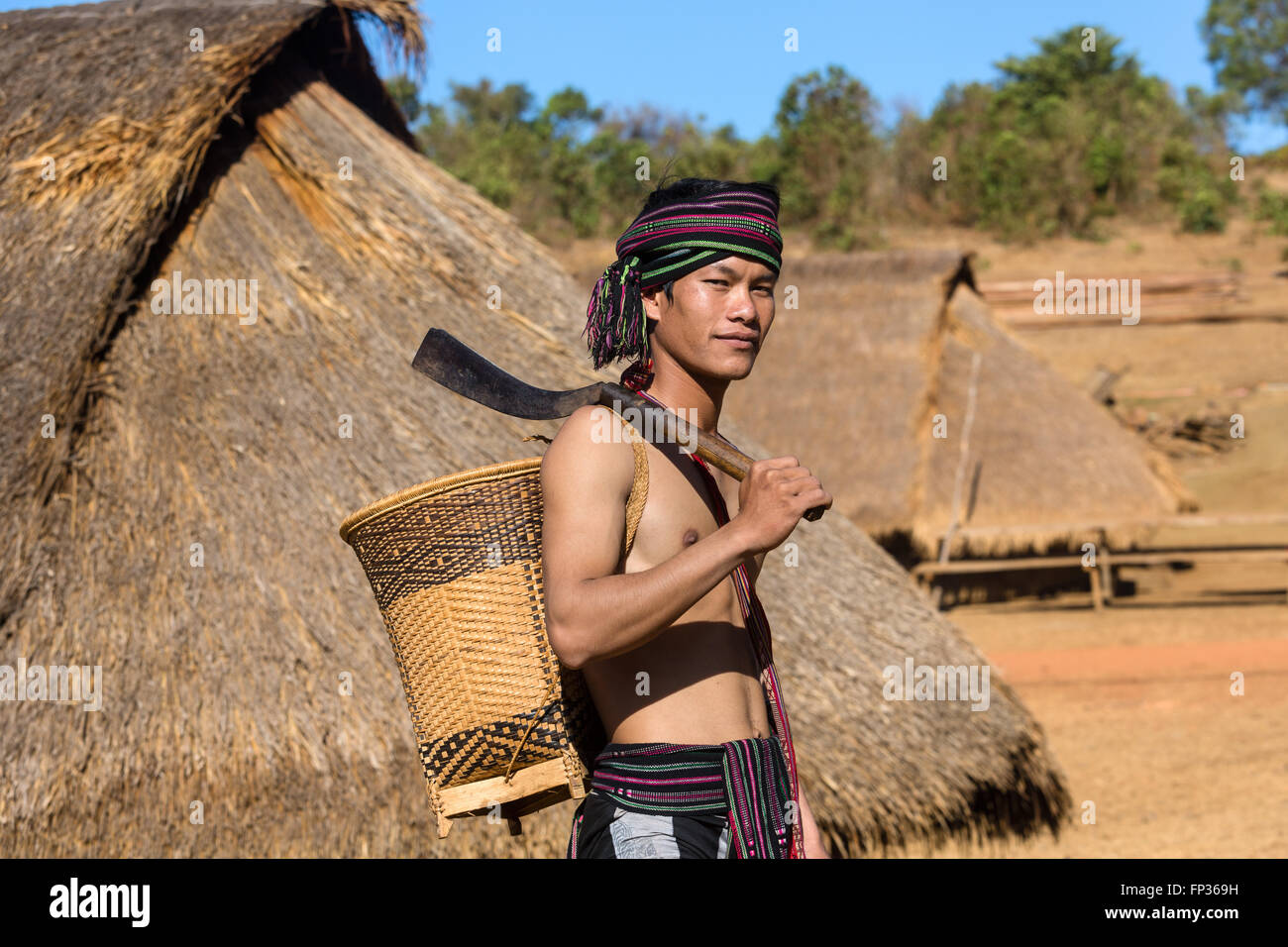 Man in traditional costume in front of a Phnong house, ethnic minority, Pnong, Bunong, Senmonorom, Sen Monorom Stock Photo