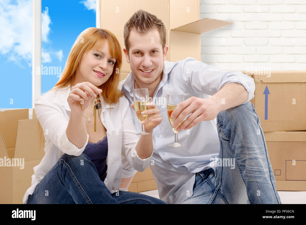 an happy couple celebrating their new home, keys and champagne in hand ...