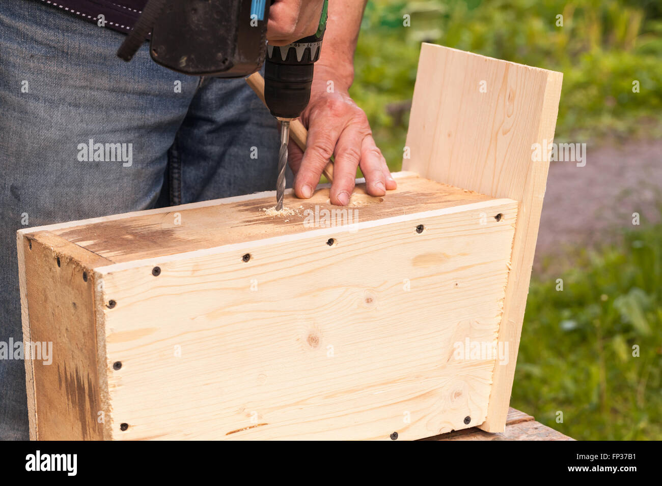 Wooden birdhouse is under construction, carpenter works with drill, closeup photo Stock Photo