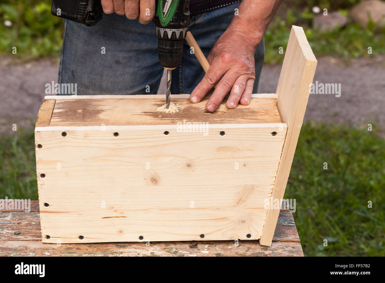 Wooden birdhouse is under construction, carpenter works with drill, close-up photo Stock Photo