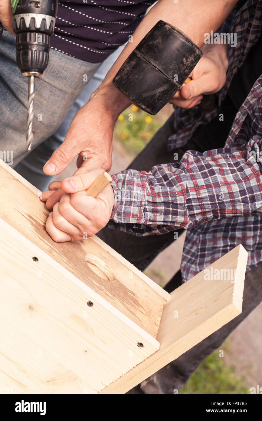 Wooden birdhouse is under construction, carpenters work with rubber hummer and drill Stock Photo
