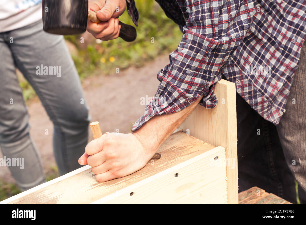 Wooden birdhouse is under construction, carpenter works with rubber hummer Stock Photo