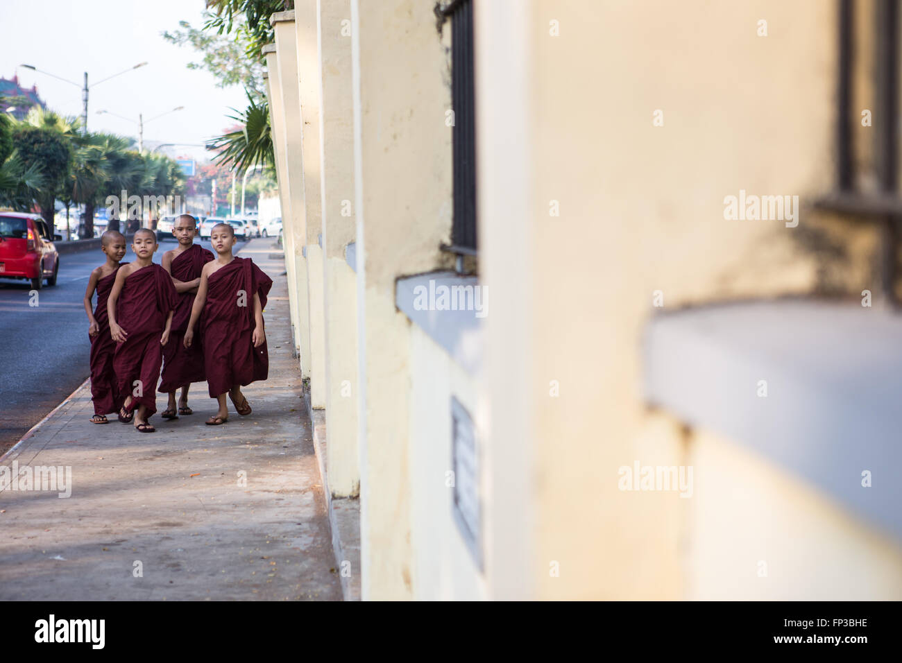 Four young monks in deep red robes walking down the street in Yangon, Myanmar (Asia) Stock Photo