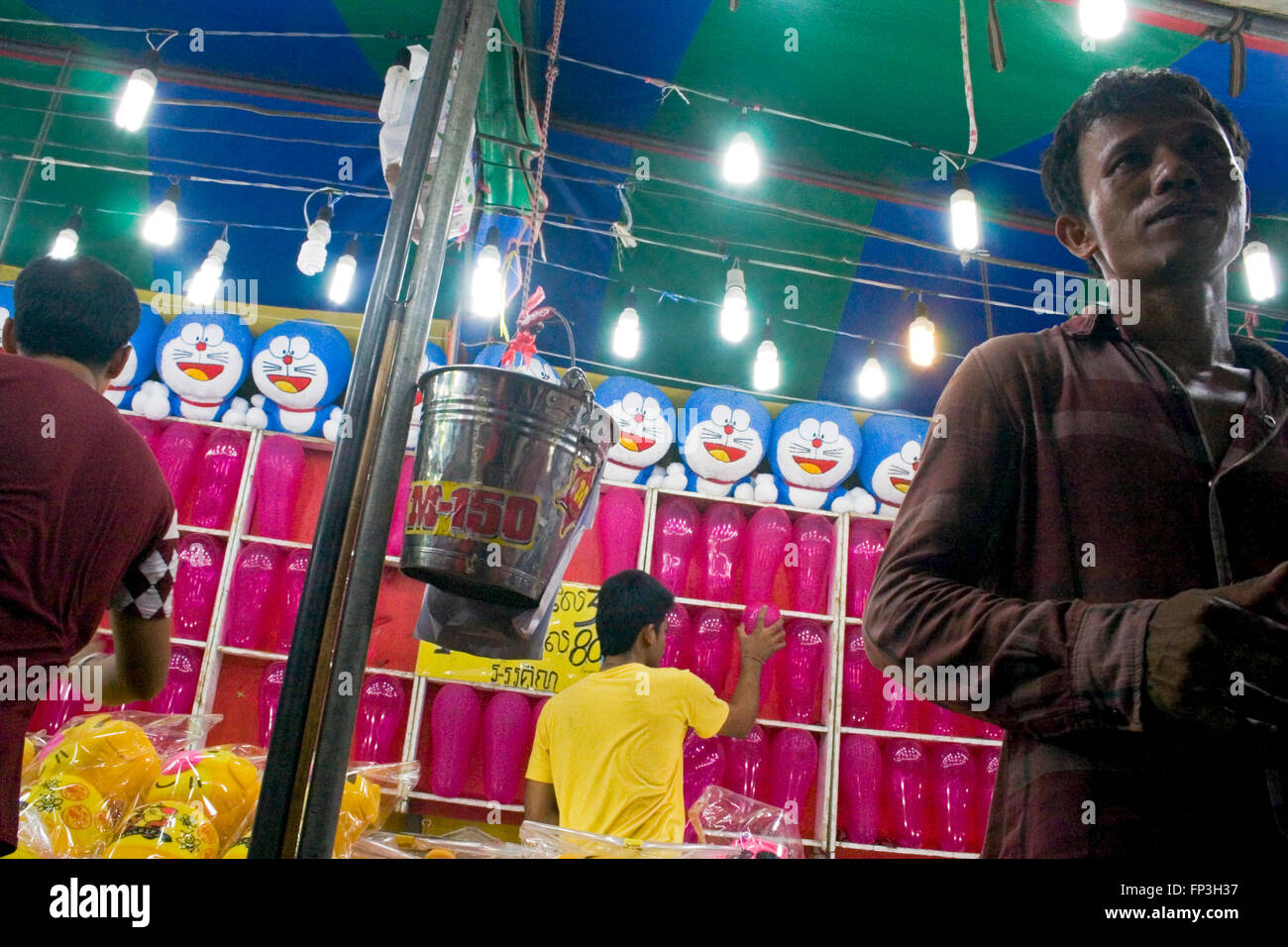 People enjoy throwing darts at balloons at a street fair in Kampong