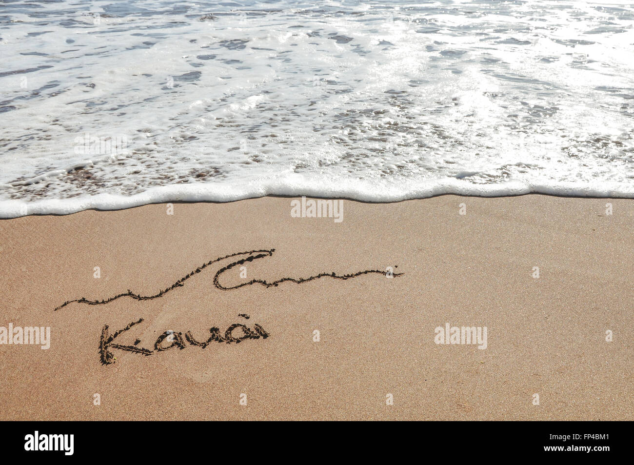 Kauai message in the sand beach with ocean sea water wave approach in Hawaii Stock Photo