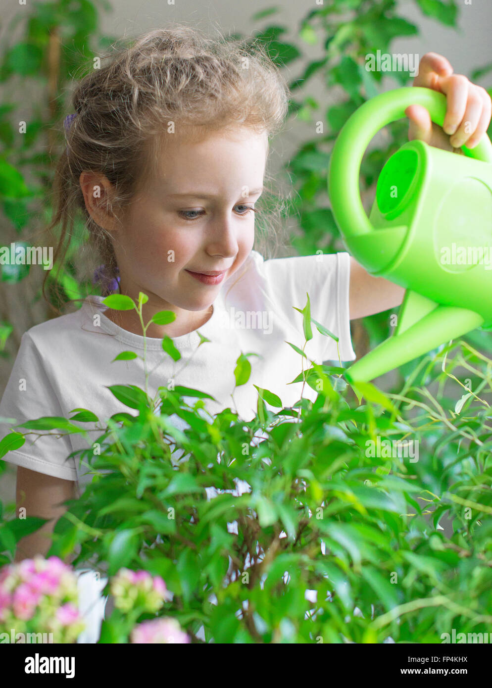 Cute little girl watering flowers at home. Stock Photo