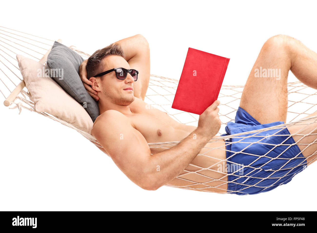 Relaxed young man lying in a hammock and reading a book isolated on ...