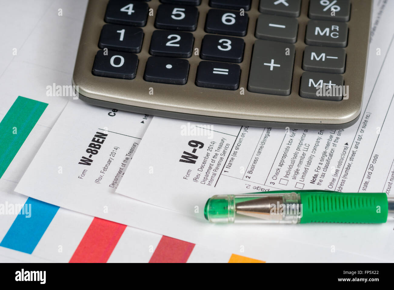 tax reporting forms with closed green pen and calculator Stock Photo