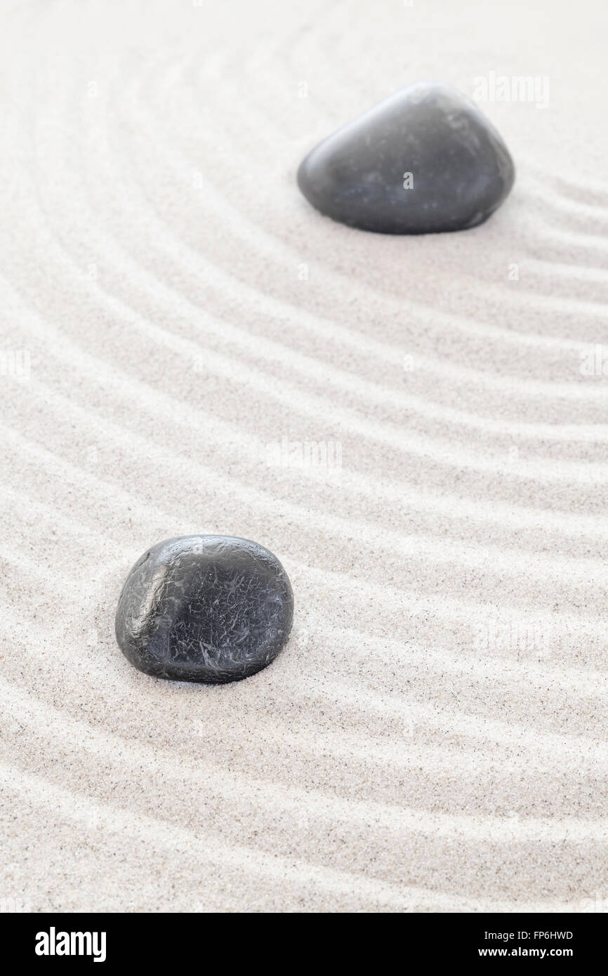 Two black stones in sand, spa or zen concept. Stock Photo