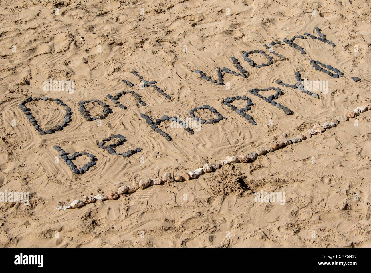 Don't Worry Be Happy, with stones in sand. Stock Photo