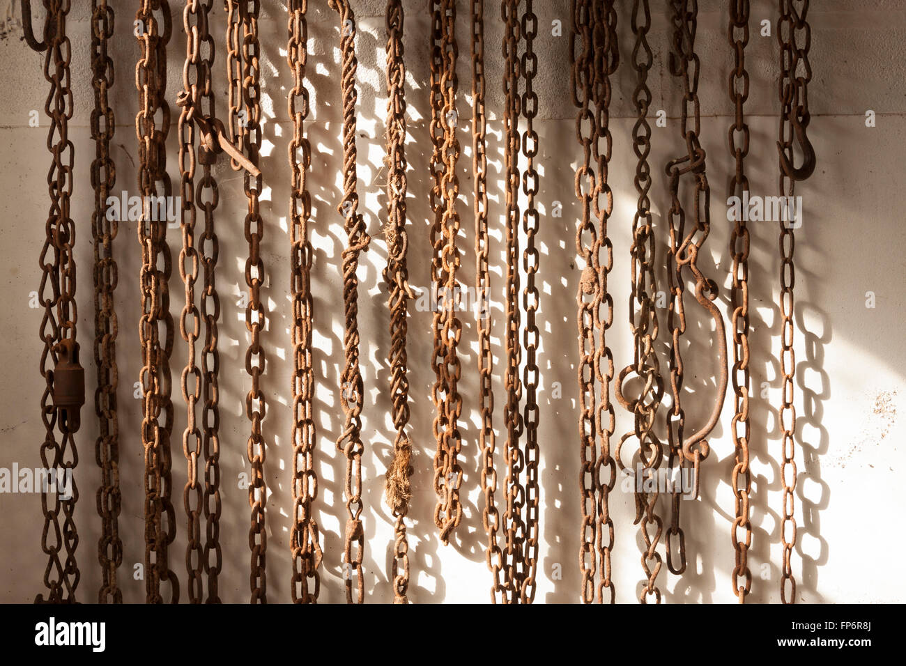 Rusty chains hanging on sunlit barn wall Stock Photo Alamy
