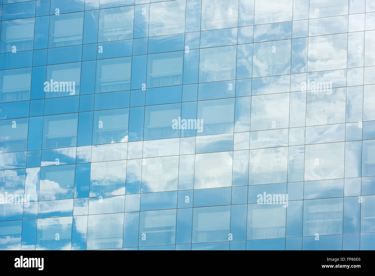 blue sky and clouds reflected in windows of modern office building ...