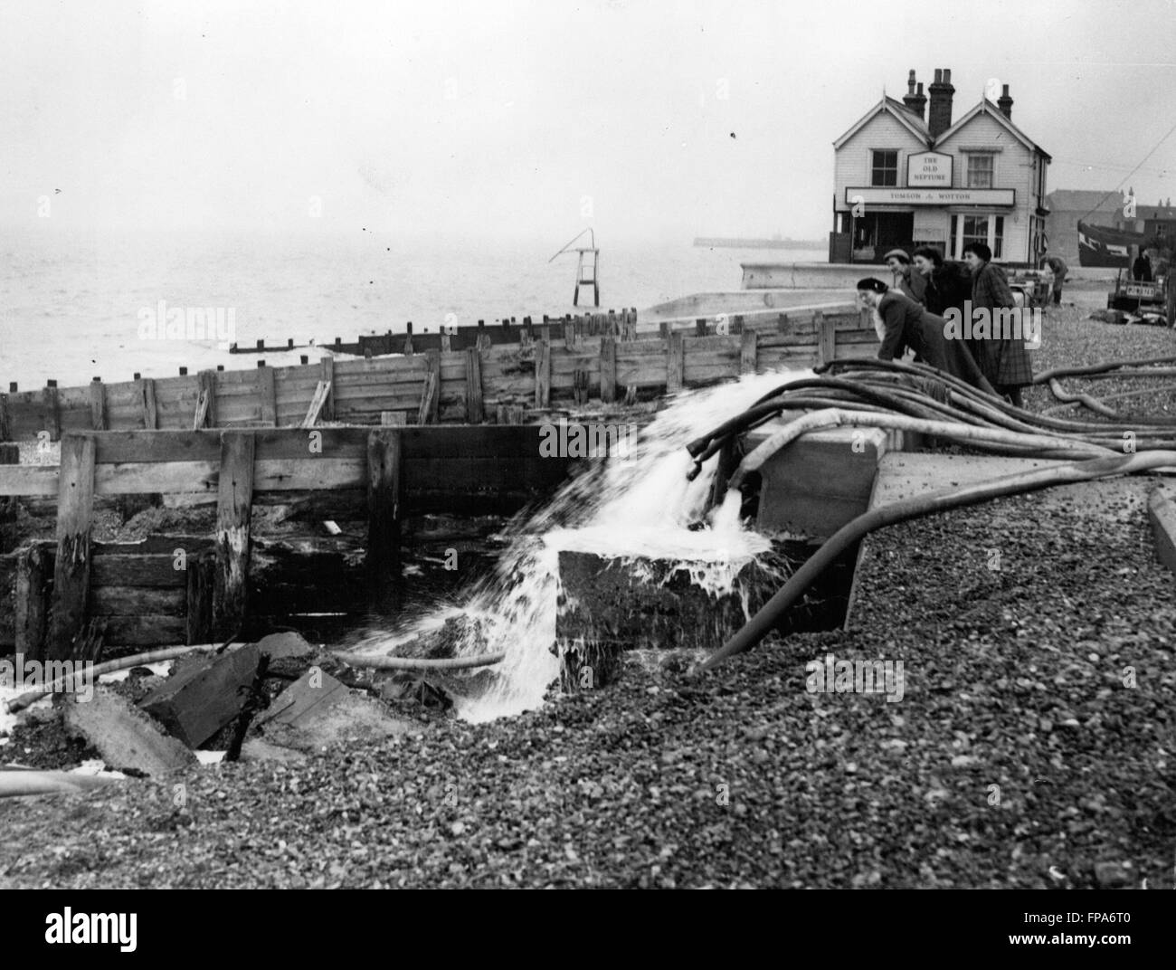 1962 - After The Flood - Scenes At Whitstable. Back Into The Sea - Goes The Water. Keystone Photo Shows:- Some of the locals seen as they watch the water pouring back into the sea from the fire hoses - during Operation Pump-Out' at Whitstable, Kent, today. © Keystone Pictures USA/ZUMAPRESS.com/Alamy Live News Stock Photo