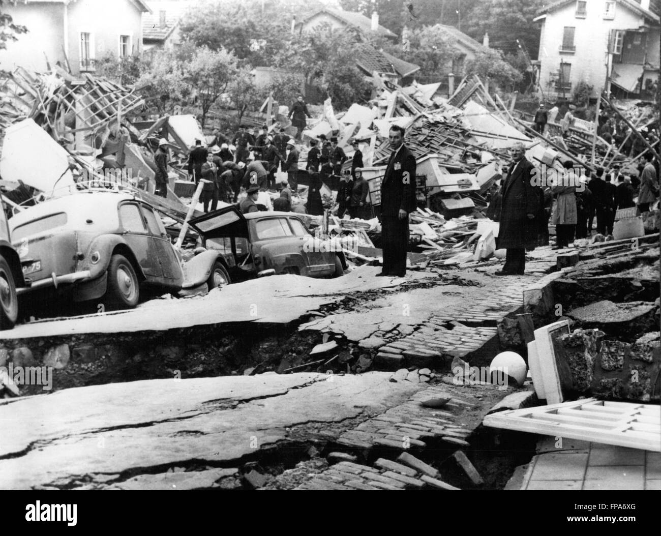 1962 - Seven killed In Landslide In Paris Suburb. Seven people were killed and 23 injured when half a square mile of the Paris suburb of Clamart subsided this morning, smashing 25 houses, a ceramics factory and a three-storey block of flats. About a dozen workers are believed to be buried alive in the factory ruins. Keystone Photo Shows:- Cars are seen on a collapsed roadway as rescue workers toil among the wreckage in the background - after today's disaster at Clamart. © Keystone Pictures USA/ZUMAPRESS.com/Alamy Live News Stock Photo