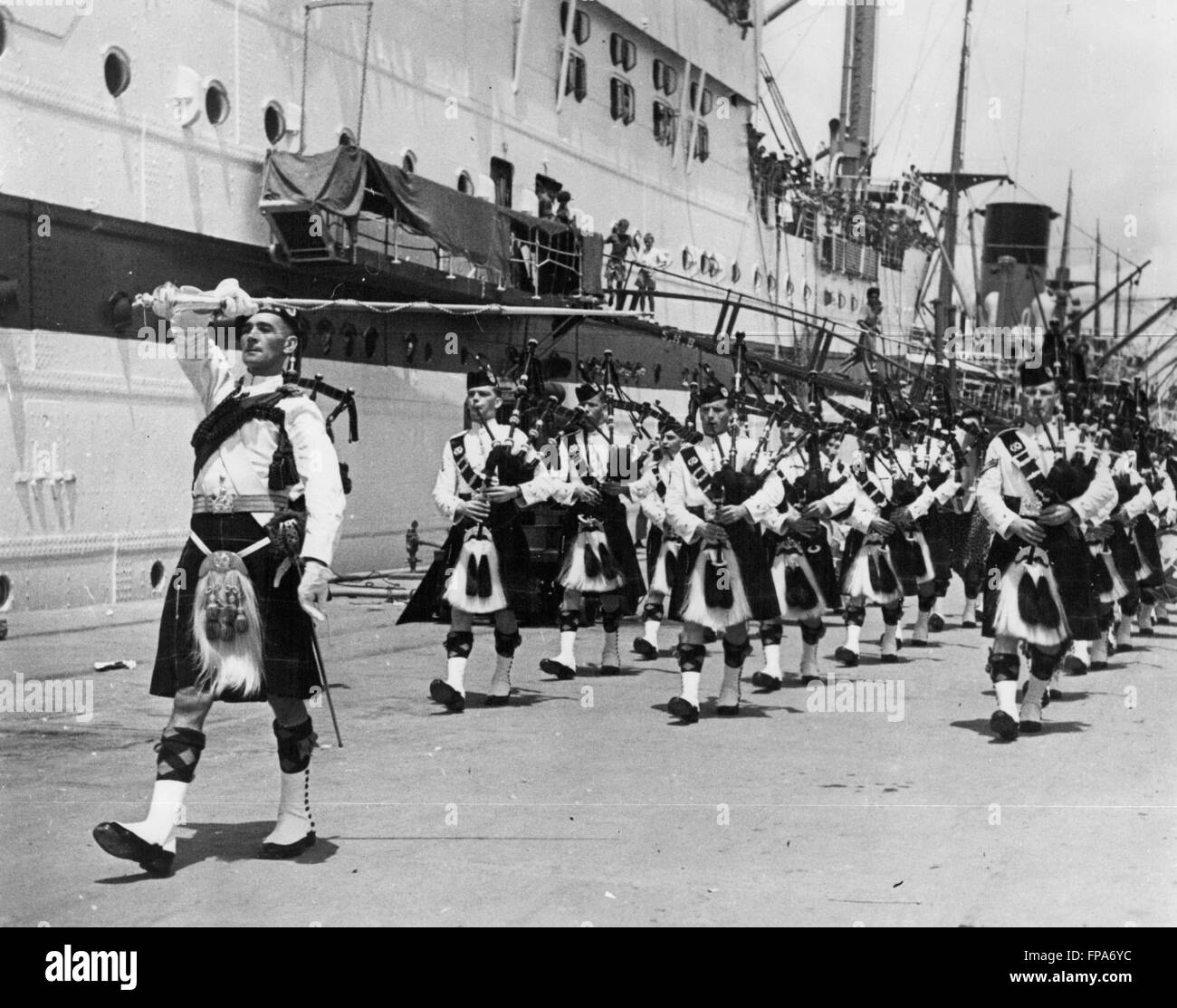 1962 - Malaya vets will Parade for the Queen: After nearly three years of Jungle fighting in Malaya, the 1st Battalion, the Cameroonians, have left for Scotland where they will perform ceremonial duties during the Queen's visit, June 23-29. The British-led battle against Communism in Malaya, which involves a total force of nearly 300,000 men and so far has cost the equivalent of 24 million, is now entering its sixth year. Photo Shows The Cameroonians, sailing from Singapore, are given a send-off by pipers and drummers of the 1st Battalion Gordon Highlanders who traveled from Malaya for the occ Stock Photo