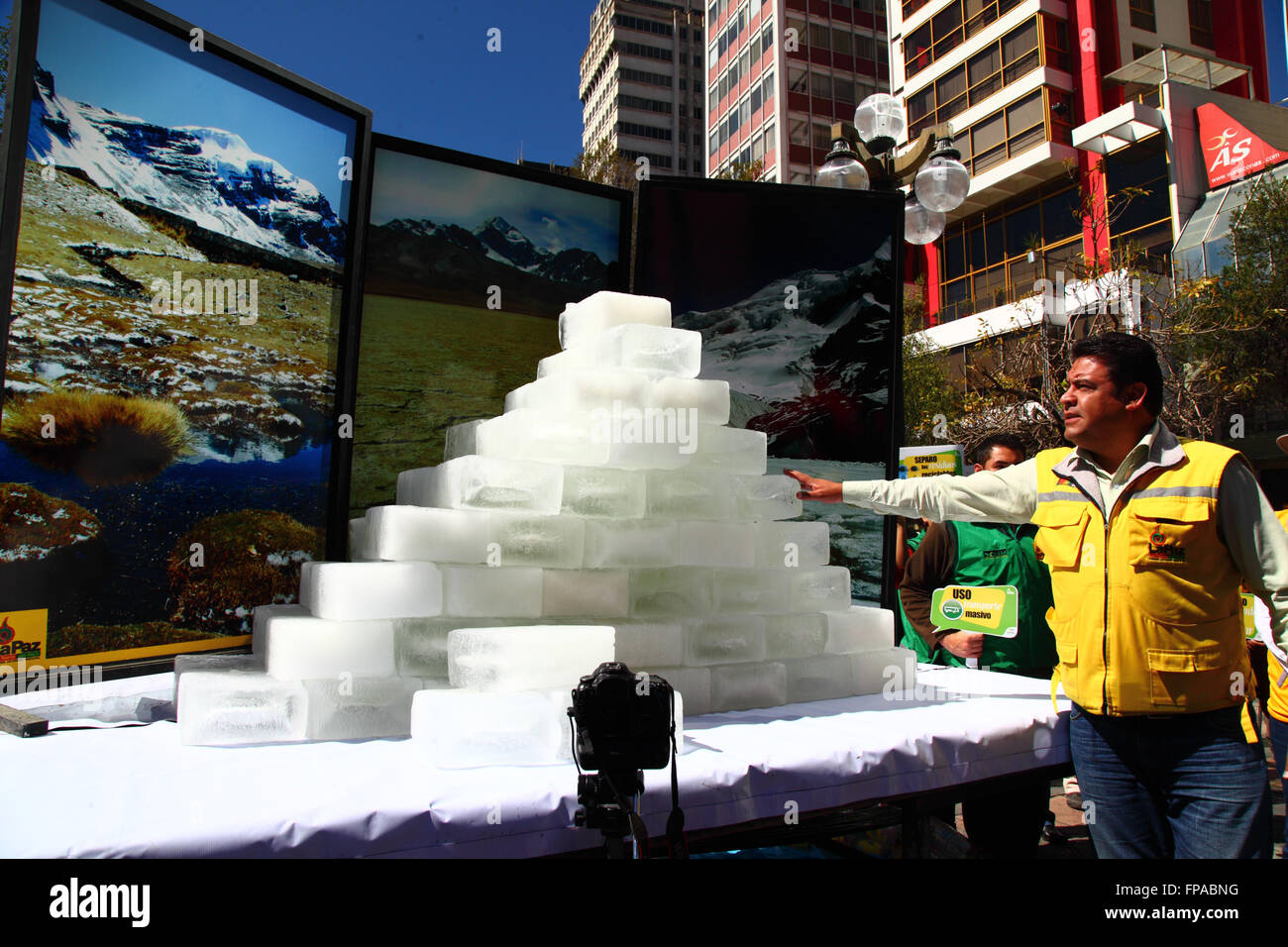 La Paz, Bolivia, 18th March 2016. The mayor of La Paz Luis Revilla stands next to blocks of ice as they slowly melt in front of photos of Bolivia's mountains at an event organised by the La Paz City Government. The glaciers in Bolivia and the central Andes are some of the fastest receding on the planet, and their disappearance is causing environmental changes and water shortages in many parts of the region. Credit:  James Brunker / Alamy Live News Stock Photo