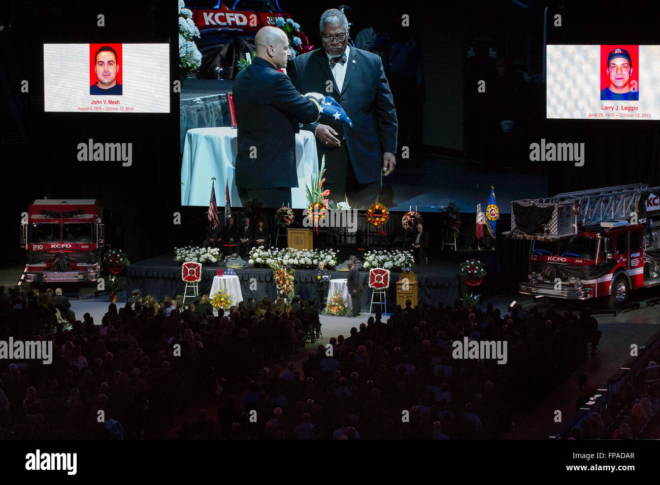 Kansas City, Missouri, USA. 18th Mar, 2016. Reference to Kansas City's Memorium to fallen firefighters John Mesh (photo on left) and Larry Leggio (photo on right). Larry J. Leggio (Truck 2 - Station 17) and John V. Mesh (Pumper 10 - Station 10) gave their lives October 12, 2015 at a building fire in the neighborhood of Independence and Prospect Avenue. They perished when a structural wall collapsed upon them. Larry Leggio was a 17-year veteran and John Mesh a 13-year veteran of the Kansas City Fire Department. Pictured at center screen handing the flag of honored service is Paul Berardi, Chi Stock Photo