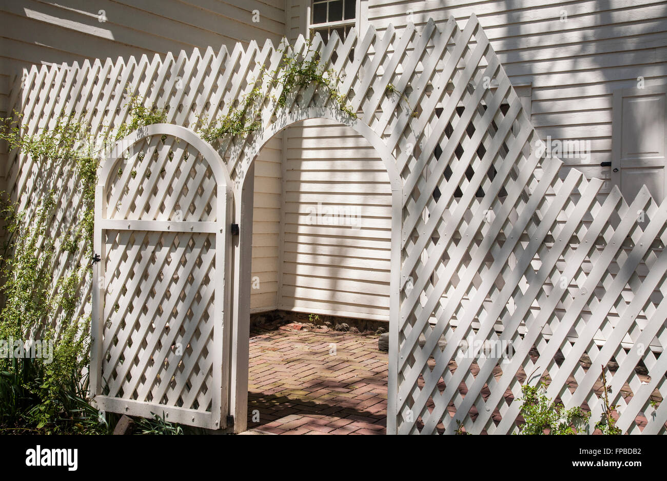 Vintage white lattice fence wall and wooden gate of a garden room Stock