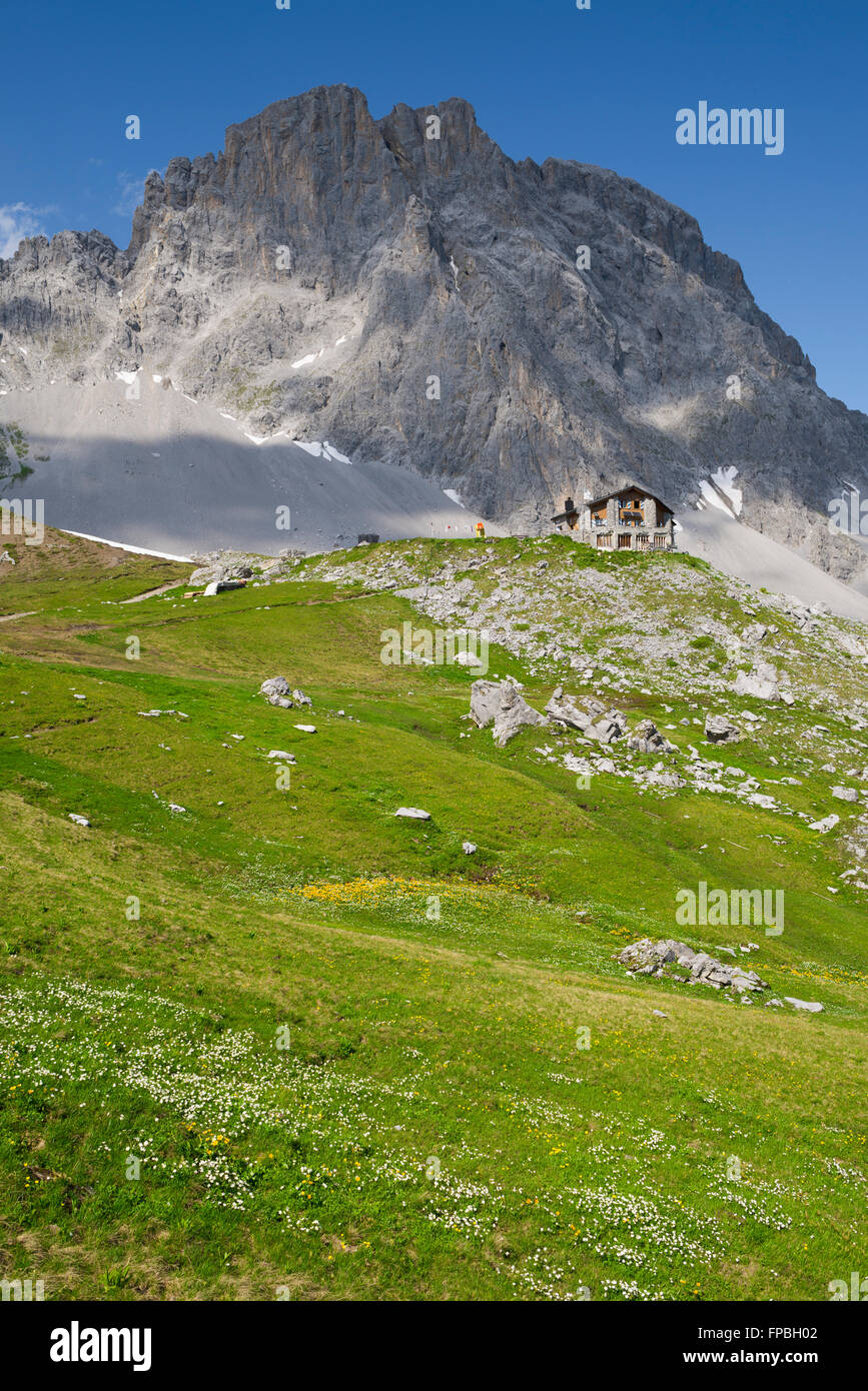 The Carschina mountain hut in front of the step rock face of the Mount Sulzfluh , canton of Grisons in Switzerland Stock Photo