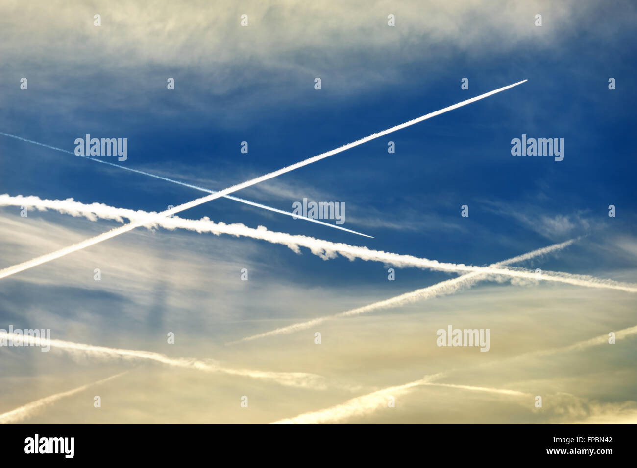 Crossed contrails in the sky with two flying past airplanes Stock Photo