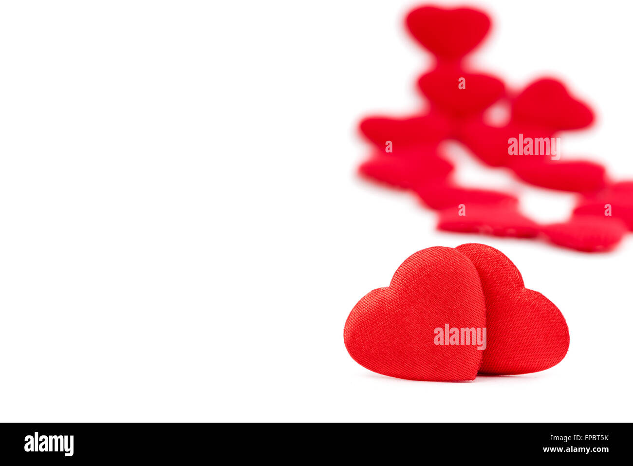 Two red hearts isolated on white background with a few others blurred ...