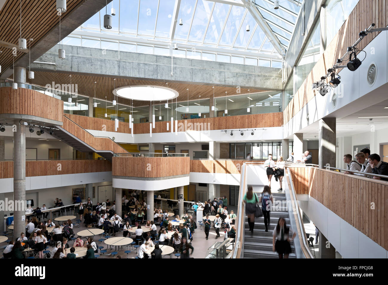 The seating area and upper gallery full of pupils, with wooden panelling design features inside Port Glasgow Shared Campus designed by Archial Norr Architects. Stock Photo