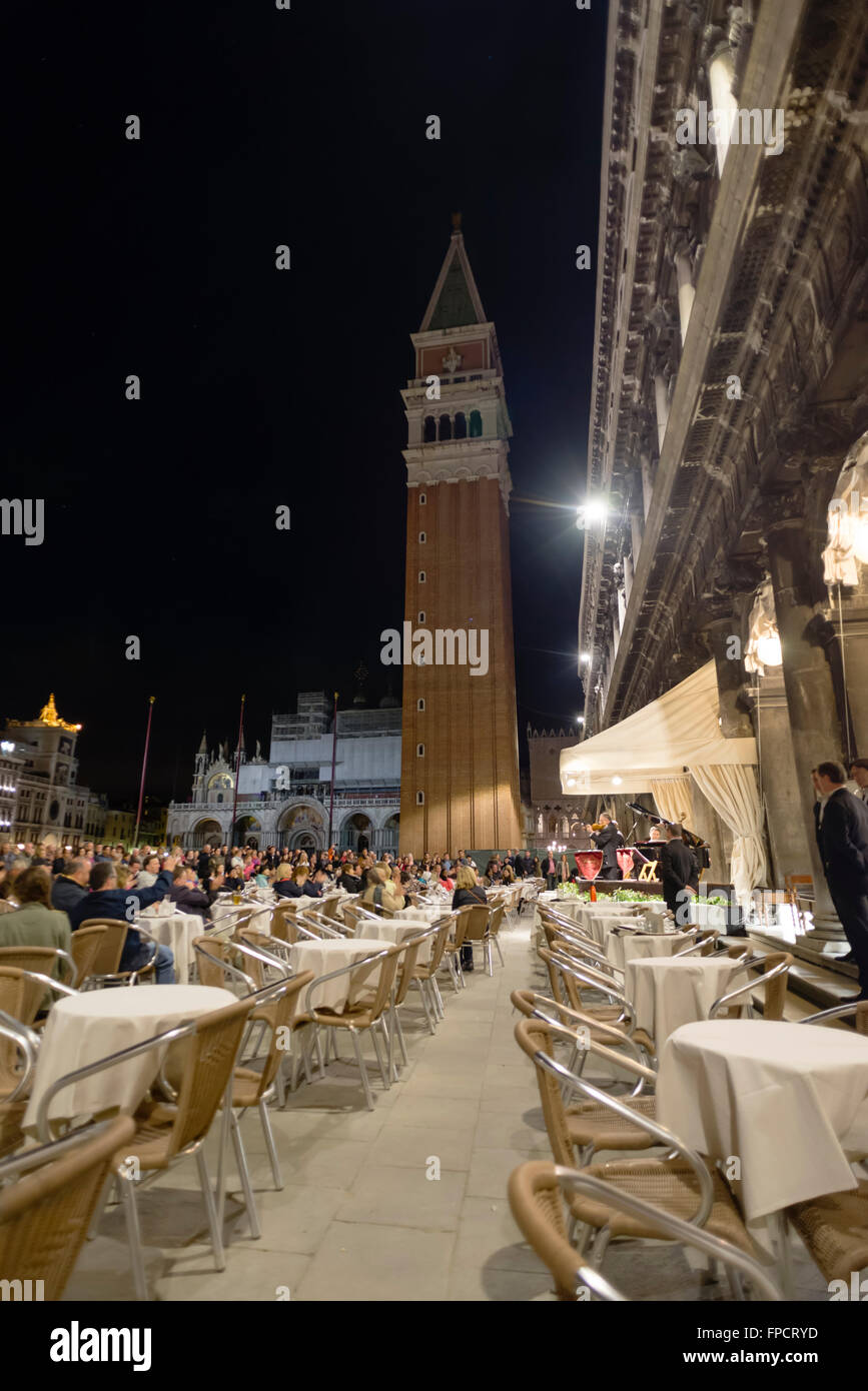 People listening to a small orchestra at an evening concert at the cafe 'Caffe Florian' on the St. Marks square in Venice Stock Photo