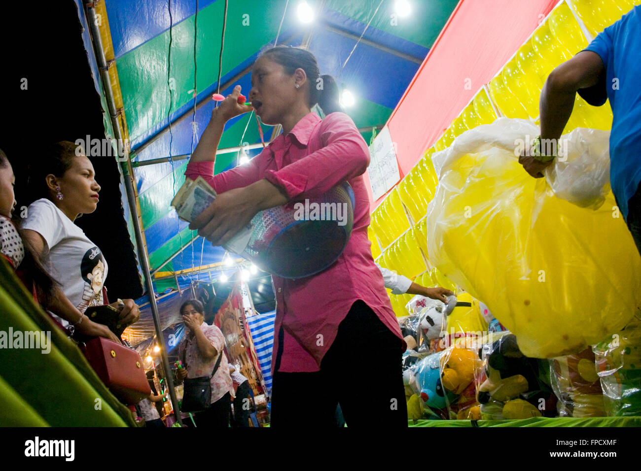 A woman is working at an arcade game where people throw darts at