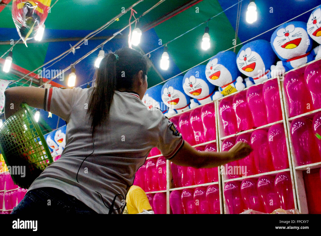 A woman is throwing darts at balloons at a street fair in Kampong Cham