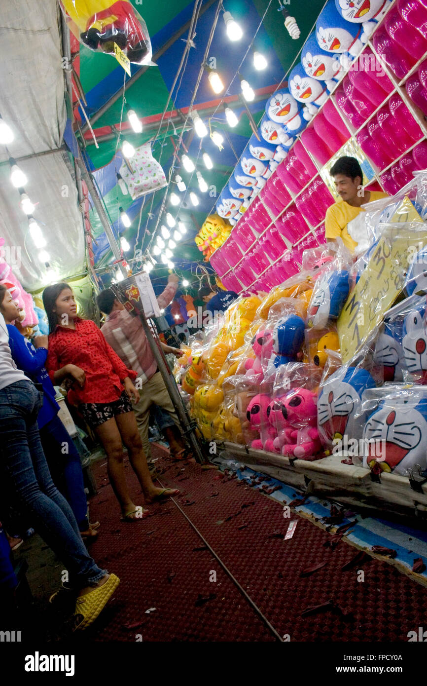 People enjoy throwing darts at balloons at a street fair in Kampong