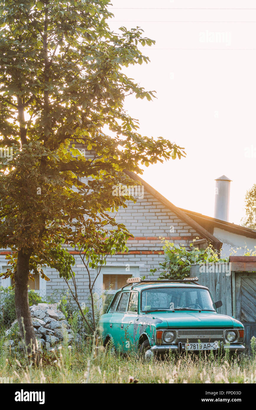 Old Soviet Car is parked near house in village countryside. Belarus. Stock Photo