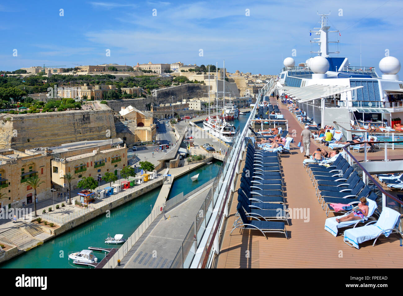 Mediterranean cruise ship liner sun deck of large tall modern ship port & city of Valletta Malta & passengers sunbathing rather than going ashore Stock Photo