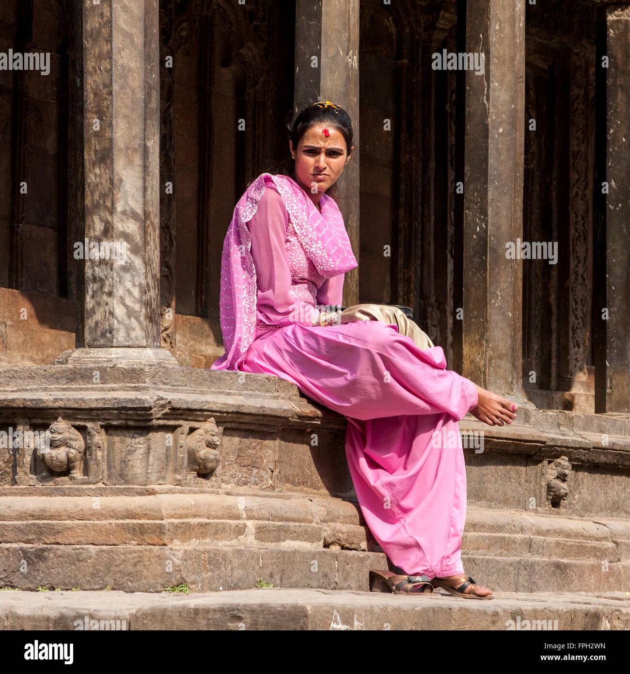Nepal, Patan.  Nepali Woman with Tika on her Forehead Sitting on Edge of Temple. Stock Photo