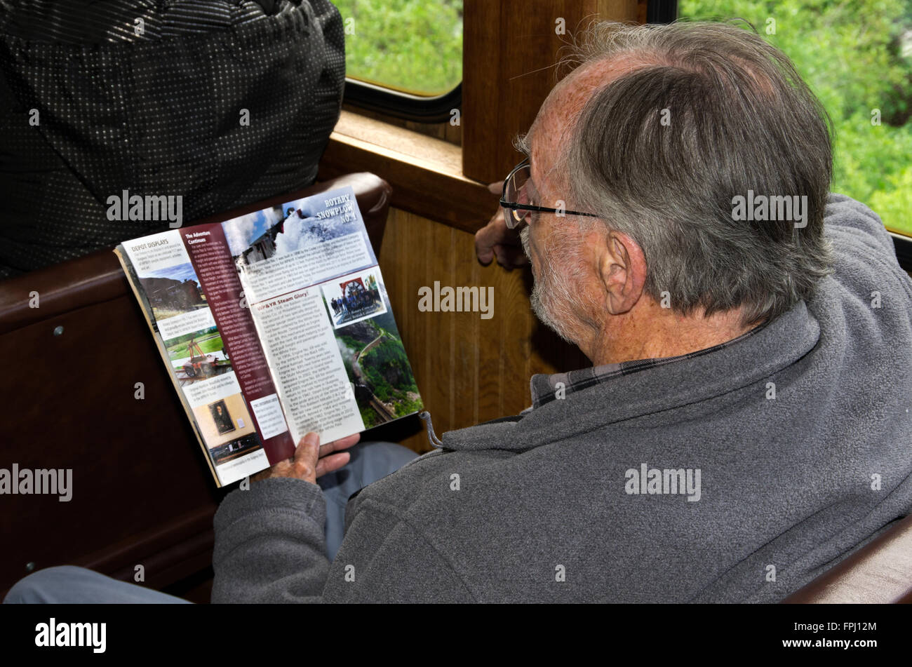 White Pass Railroad passenger in seat looks at train information Stock Photo