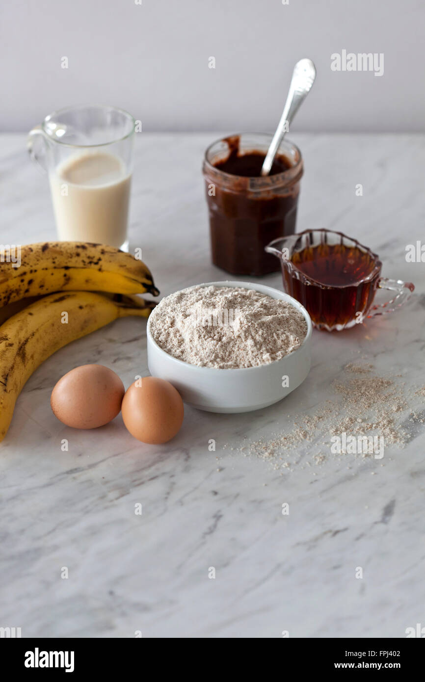 Ingredients for vegan banana bread with chocolate hazelnut spread on the white marble surface