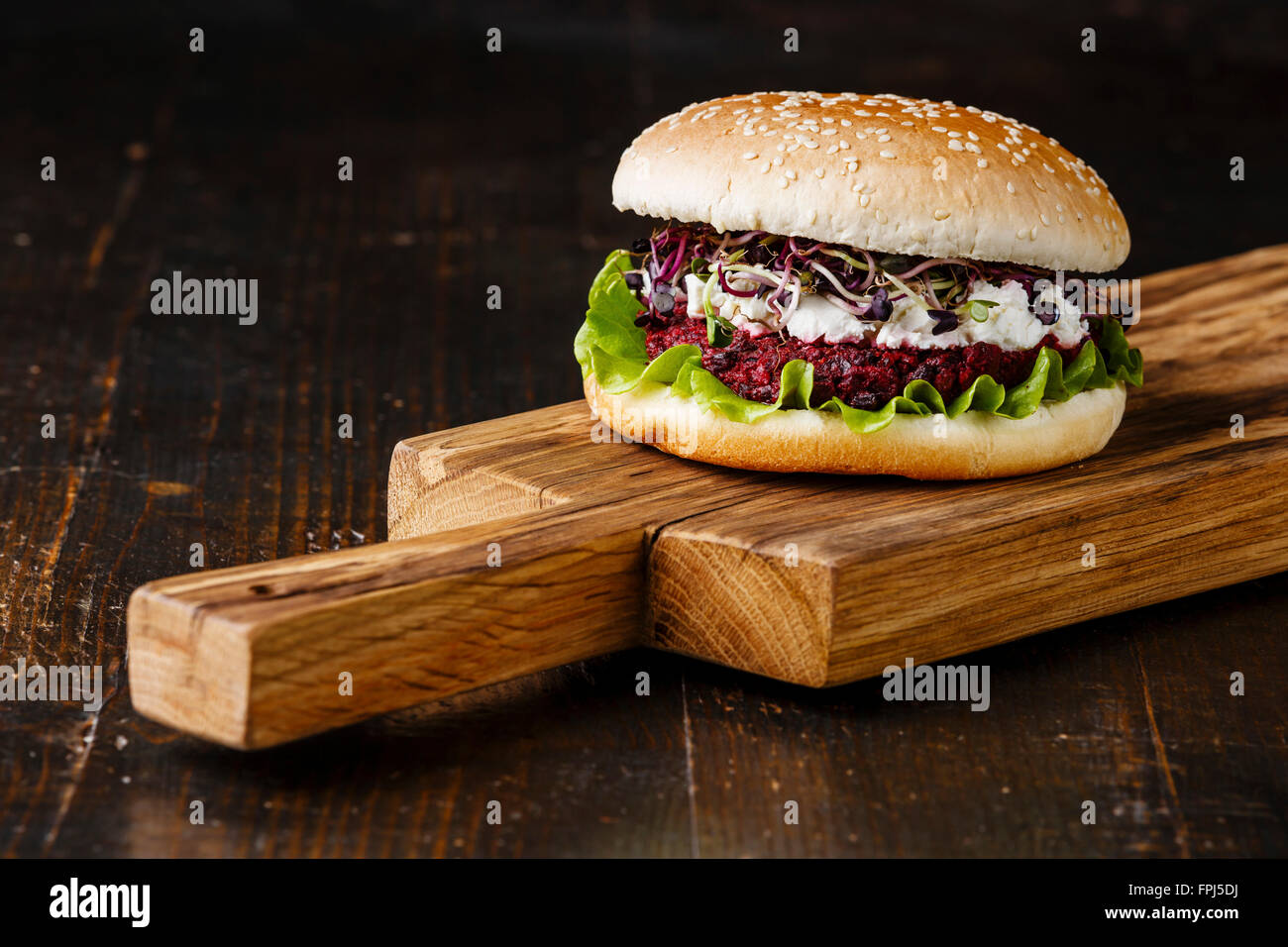 Beet burger with soft cheese and radish sprouts on dark background Stock Photo